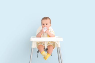 Şişe ile beslenme sandalyesinde oturan sevimli küçük bebek.