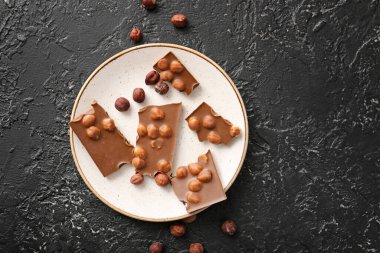 Koyu arkaplanda lezzetli çikolata ve fındık tabağı.