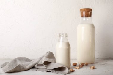 Bottles of tasty cashew milk on white table clipart