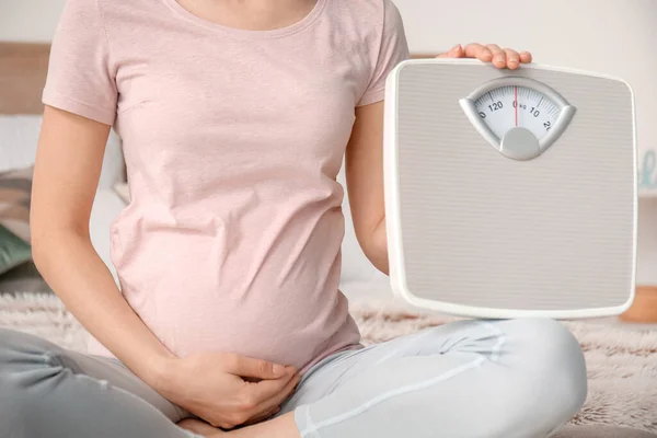 若いです妊娠中の女性で測定スケールでベッドルーム — ストック写真