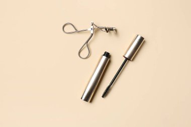 Renk arkaplanında kirpik bigudisi olan maskara