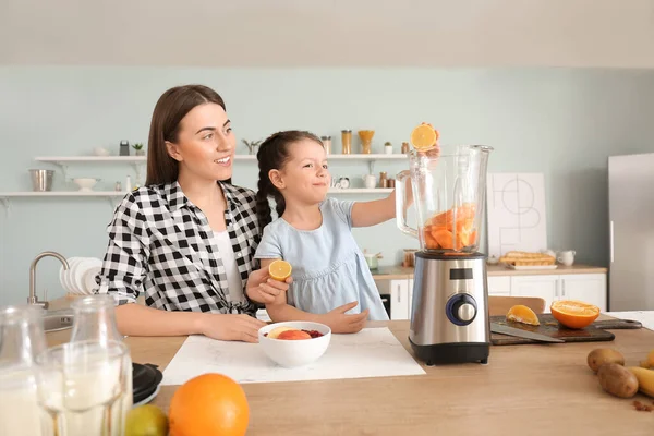 Anne ve küçük kız mutfakta sağlıklı meyve püresi yapıyorlar.
