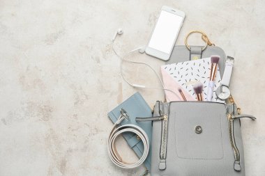 Kadın aksesuarları ve hafif arka planda cep telefonu olan şık bir çanta.