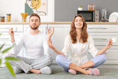 Mutlu genç çift mutfakta meditasyon yapıyor.