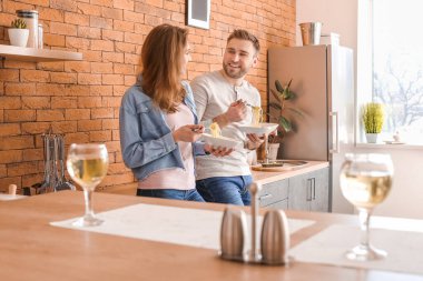 Mutlu genç çift mutfakta yemek yiyor.