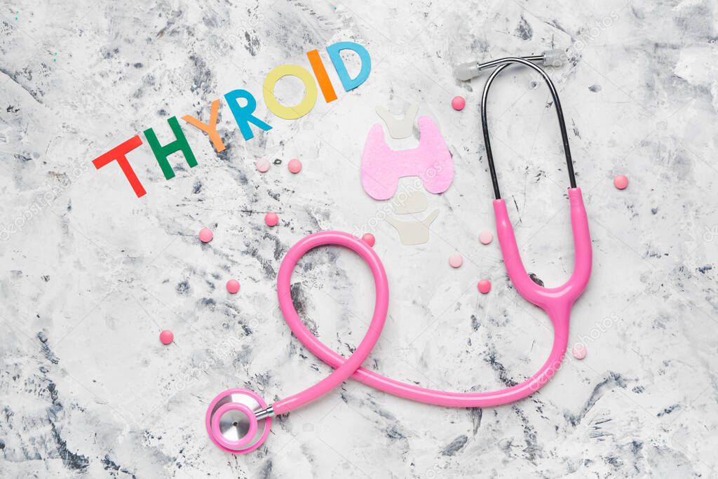 Text THYROID with pills and stethoscope on white background
