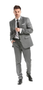 Beyaz arka planda zarif takım elbiseli yakışıklı bir genç.