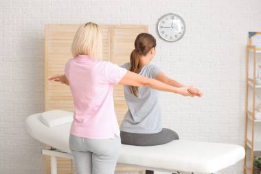 Tıp merkezinde kadın hastayla çalışan masaj terapisti.