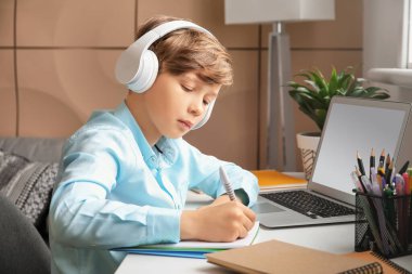 Evde ders çalışan sevimli küçük bir çocuk. Çevrimiçi eğitim kavramı