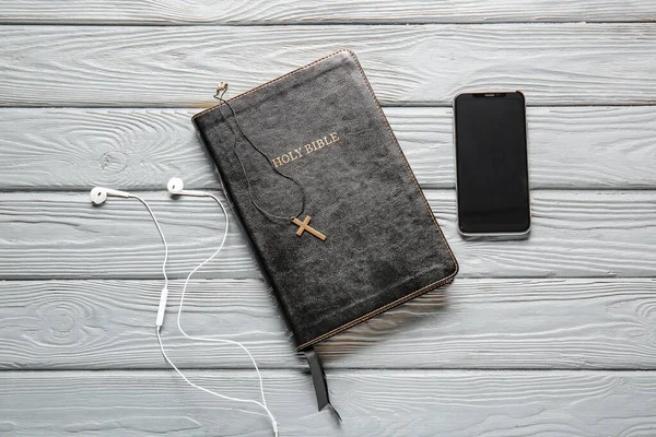神圣的圣经 木制背景的手机和耳机 — 图库照片