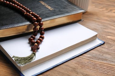 Kutsal İncil ve ahşap arka planda tespih.
