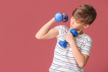 Renkli arka planda dambılları olan sportif küçük çocuk.