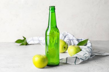 Hafif arkaplanda bir şişe elma şarabı.