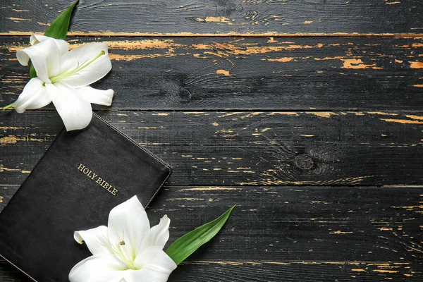 Holy Bible and flowers on wooden background