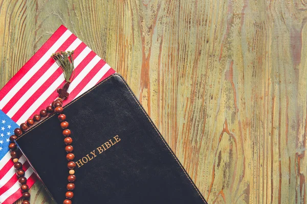 圣经上 美国国旗和木制背景的念珠 — 图库照片