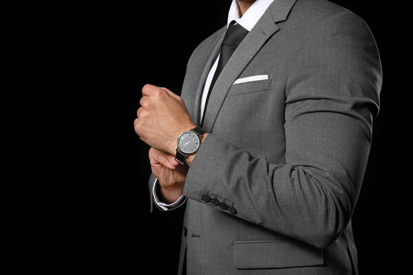 Handsome young man in elegant suit on dark background
