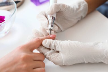 Manikür ustası kadın müşteriyle güzellik salonunda çalışıyor.