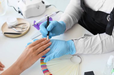 Manikür ustası kadın müşteriyle güzellik salonunda çalışıyor.