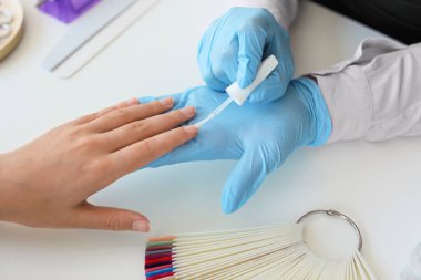 Manikür ustası kadın müşteriyle güzellik salonunda çalışıyor.