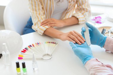 Manikür ustası kadın müşteriyle güzellik salonunda çalışıyor.