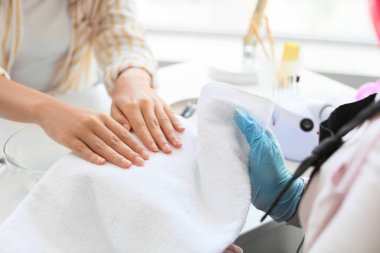 Manikür ustası kadın müşteriyle güzellik salonunda çalışıyor.