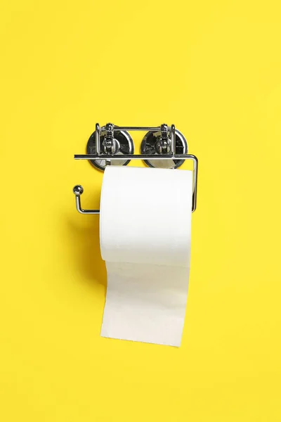 Holder with roll of toilet paper on color background
