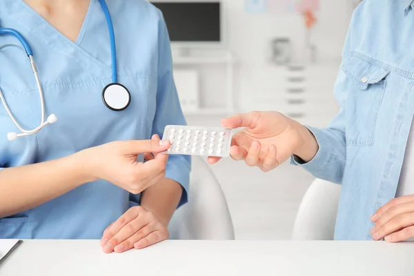 Female gynecologist and patient with birth control pills in clinic