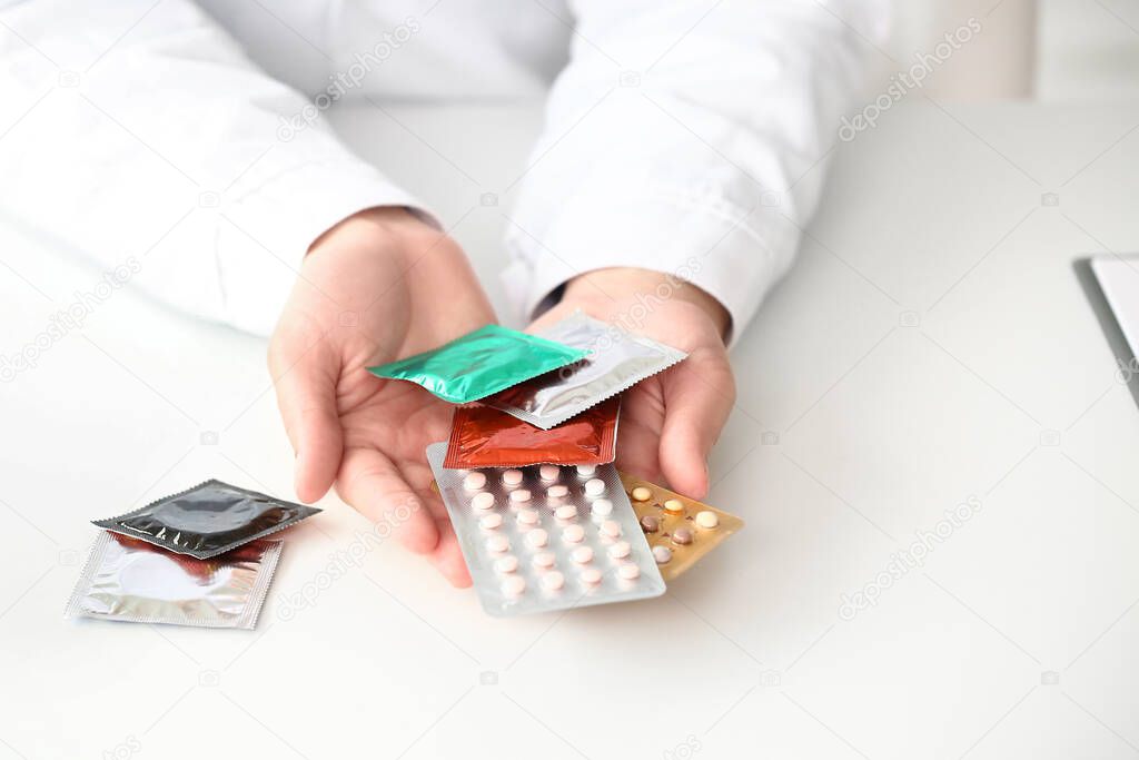 Female gynecologist with different contraceptives in clinic, closeup