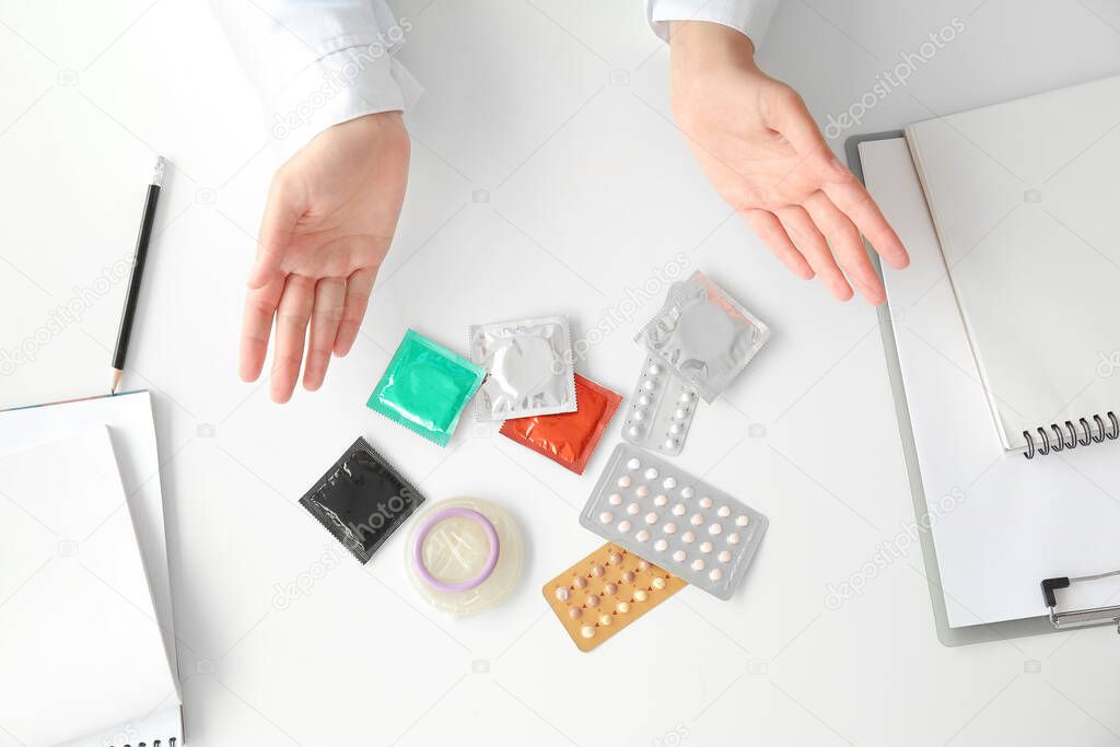 Female gynecologist with different contraceptives in clinic, top view