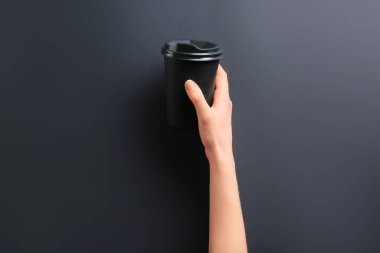 Karanlık arka planda içmek için paket servis bardağıyla.