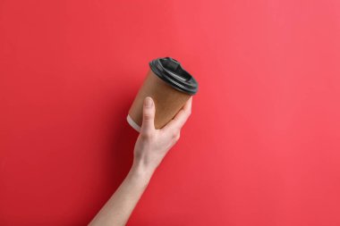 Renkli arka planda içmek için paket servis fincanı ile el.