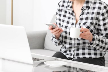 Evde cep telefonu kullanan genç bir kadın.