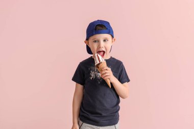 Kirli elbiseli küçük çocuk arka planda dondurma yiyor.