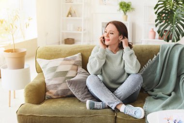 Evde cep telefonuyla konuşan güzel genç bir kadın.