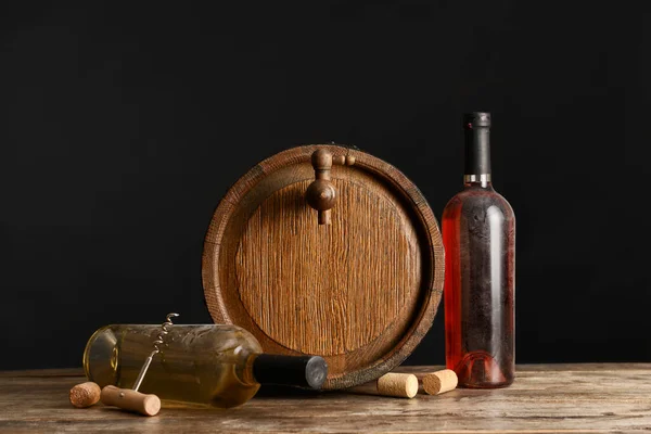 Wooden barrel and bottles of wine on dark background