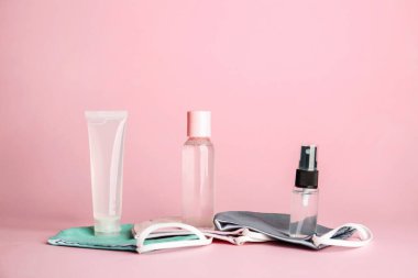 Renkli arkaplanda dezenfektan ve tıbbi maske şişeleri