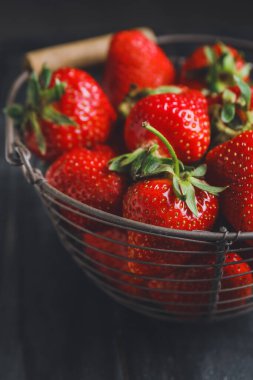 Koyu arkaplanda olgun çilekli sepet, yakın plan.