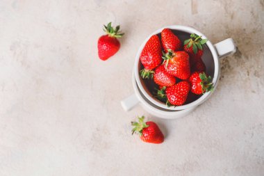 Masanın üzerinde olgun çilekli fincanlar.