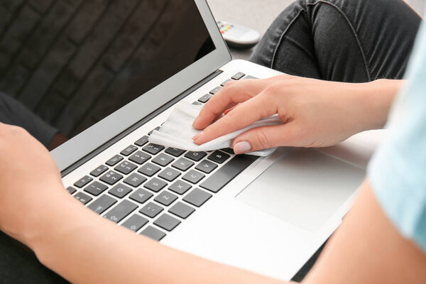 Woman disinfecting laptop at home