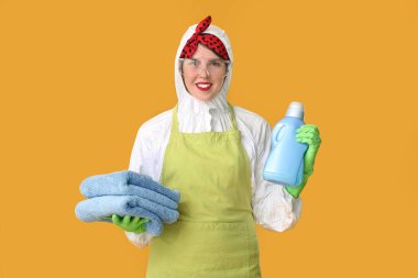 Koruyucu kostümlü ev hanımı. Deterjan ve renkli havlular.