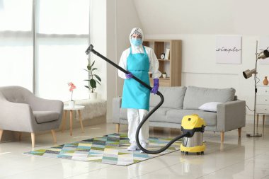 Koruyucu kostümlü ev hanımı odayı temizliyor.
