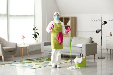Koruyucu kostümlü ev hanımı odayı temizliyor.