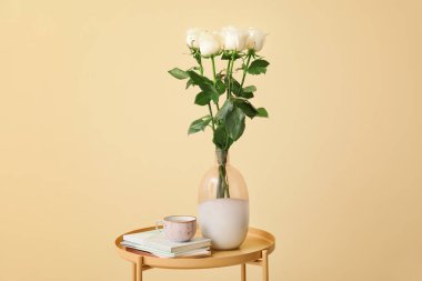 Üzerinde güzel güller ve bir fincan kahve olan vazo.