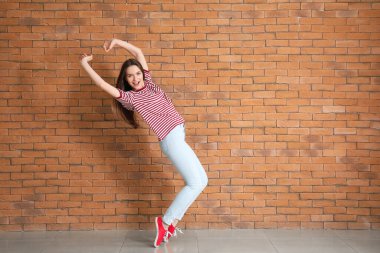 Tuğla duvarın yanında dans eden güzel genç bir kadın