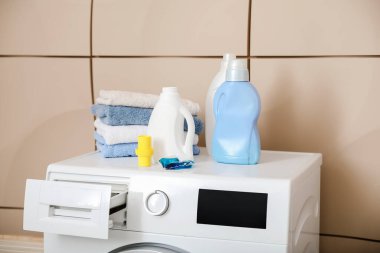 Çamaşır makinesinde farklı deterjanlar ve temiz havlular var.