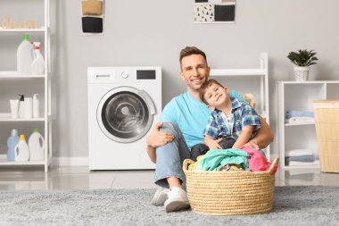 Adam ve küçük oğlu evde çamaşır yıkıyorlar.