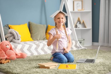 Evde ders çalışan sevimli küçük bir kız. Çevrimiçi eğitim kavramı