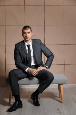 Zarif takım elbiseli yakışıklı genç adam bankta oturuyor.