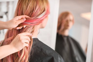 Kadın kuaför, kuaförde güzel bir genç kadının saçını yapıyor.