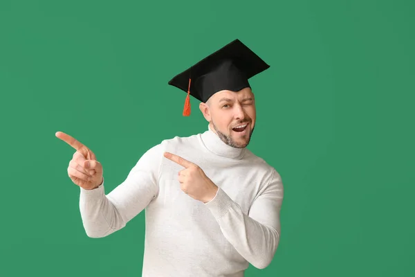 戴著毕业帽的男人指着有色彩背景的东西 — 图库照片